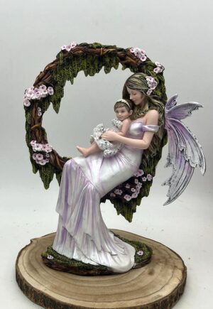 Hada Idía con su bebé en brazos, sentada en un arco de ramas con flores rosas, figura de 35 cm