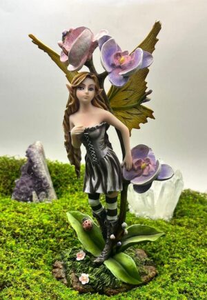 Hada Shae de 24 cm junto a tres flores lilas y rosas, con vestido gris, medias de rayas y alas amarillas