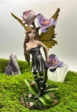 Hada Shae de 24 cm junto a tres flores lilas y rosas, con vestido gris, medias de rayas y alas amarillas